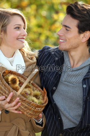 Couple gathering chestnuts in basket