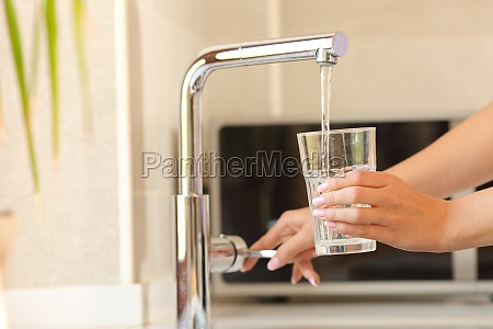 Close up of a woman hands filling a glass of tap water
