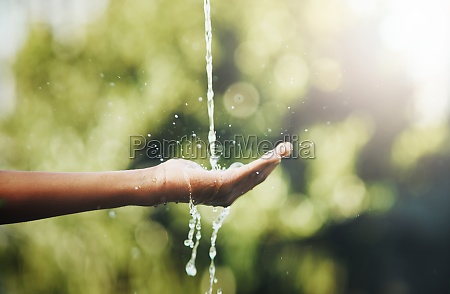 Every drop is precious. hands held out to catch a stream of water outside