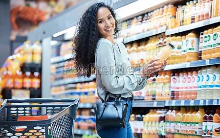 Portrait of a woman with juice while shopping in a grocery store with a retail product sale. Happy customer with a wellness,  health and diet lifestyle buying healthy groceries at a supermarket