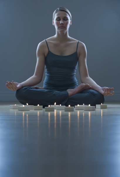 kobieta medytuje obok swieczki