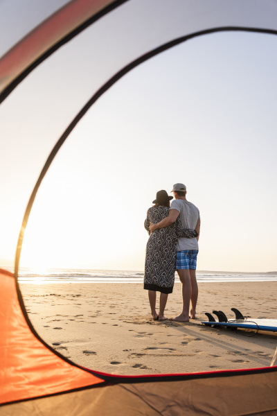 casal romantico acampando na praia abracando