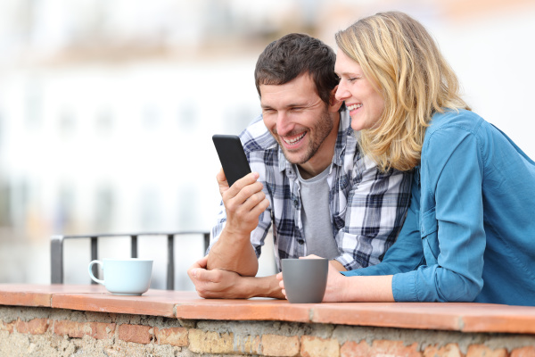 casal adulto feliz verificando telefone inteligente