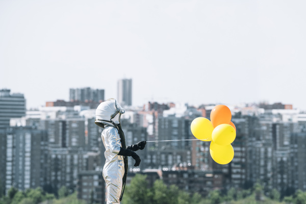 menino vestido de astronauta segurando baloes