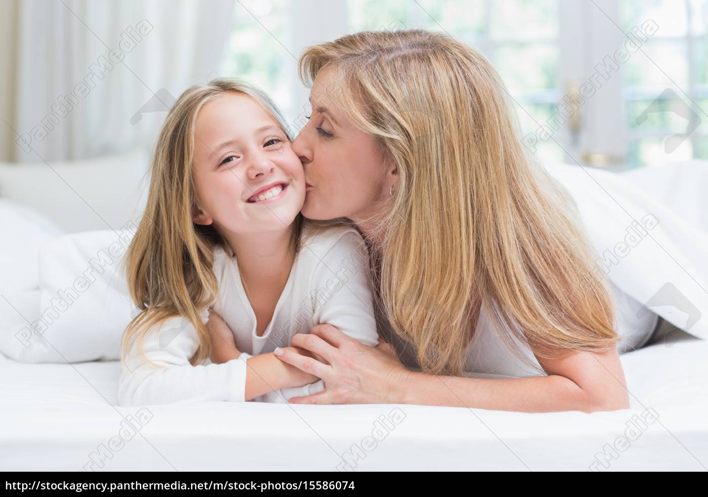 Madre besando a su hija en la mejilla en la cama - Stockphoto #15586074 |  Agencia de stock PantherMedia