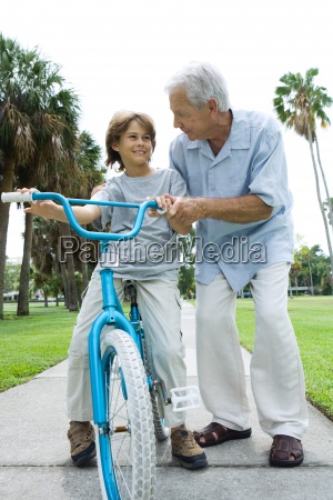 Grandfather teaching grandson to ride bicycle front - Lizenzfreies Bild ...