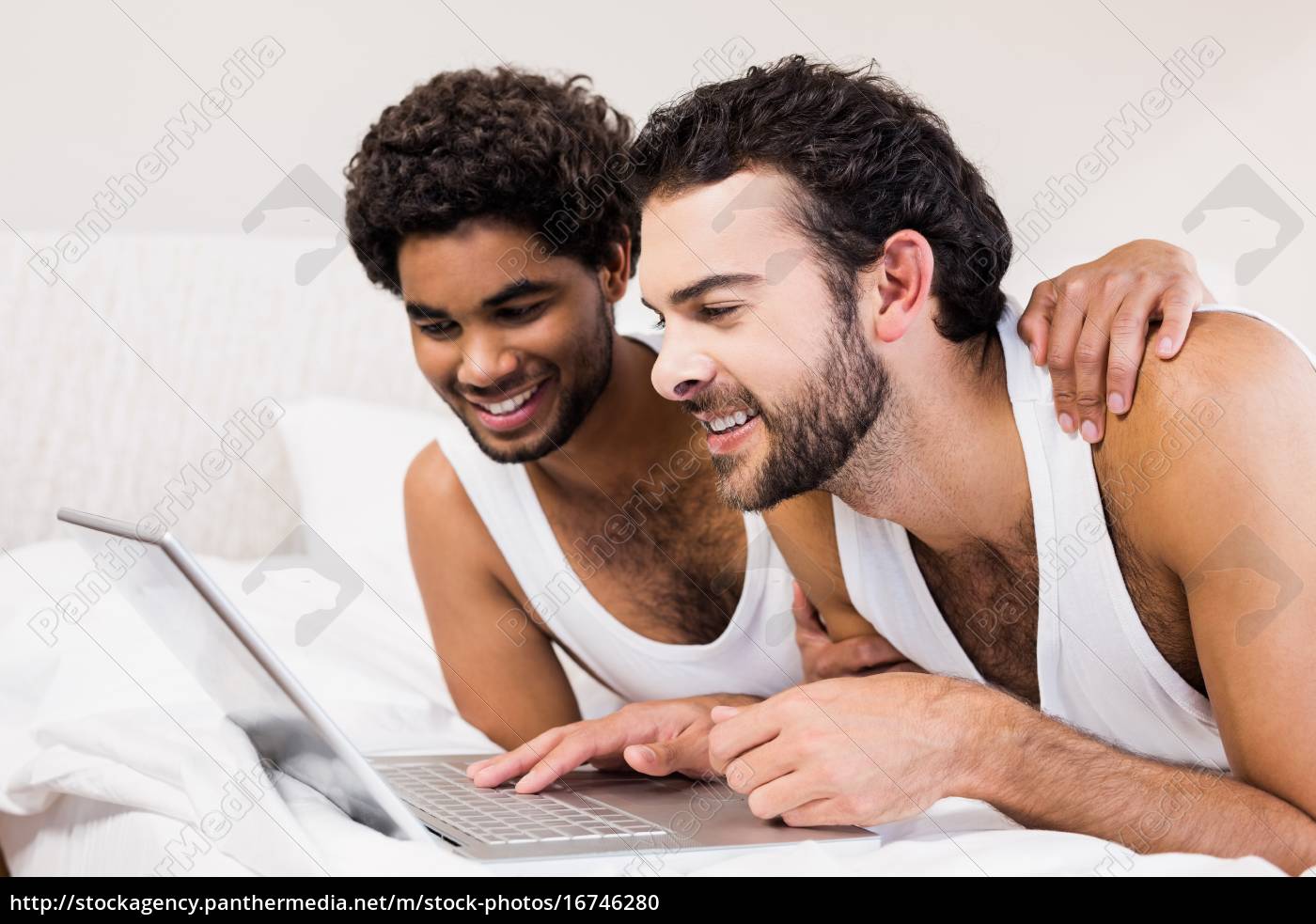 Feliz pareja gay acostado en la cama usando el - Stockphoto #16746280 |  Agencia de stock PantherMedia