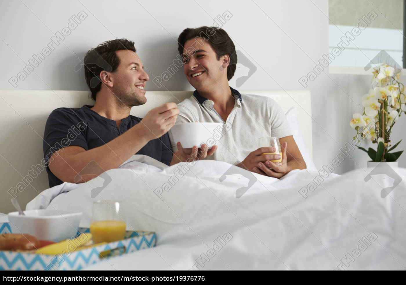 Casal gay masculino relaxa na cama comendo olhando um - Stockphoto  #19376776 | Banco de Imagens Panthermedia