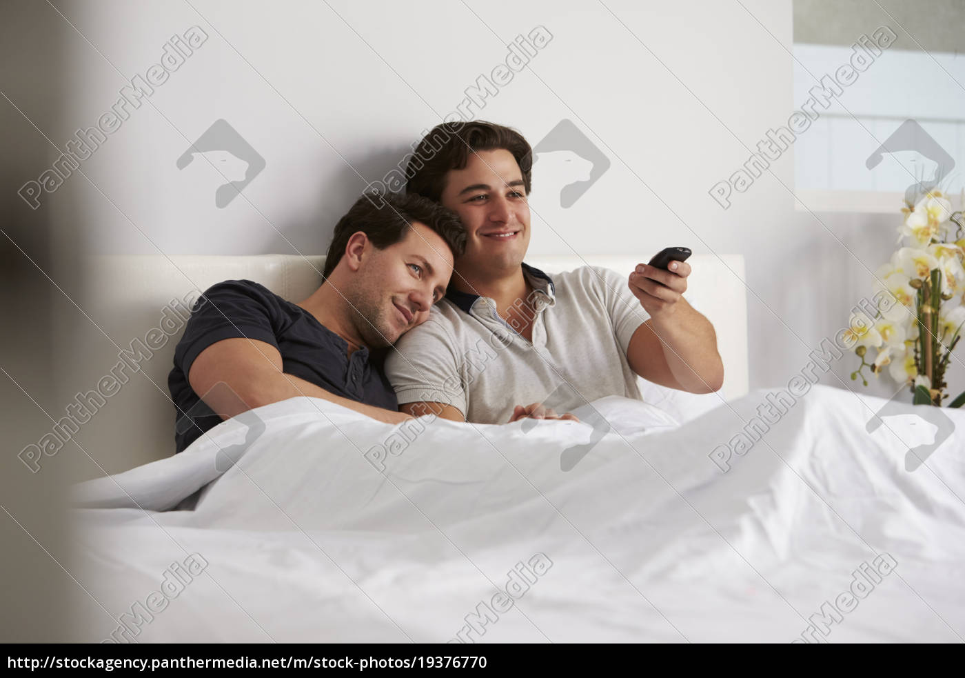 Pareja gay masculina se relaja en la cama viendo la - Stockphoto #19376770  | Agencia de stock PantherMedia