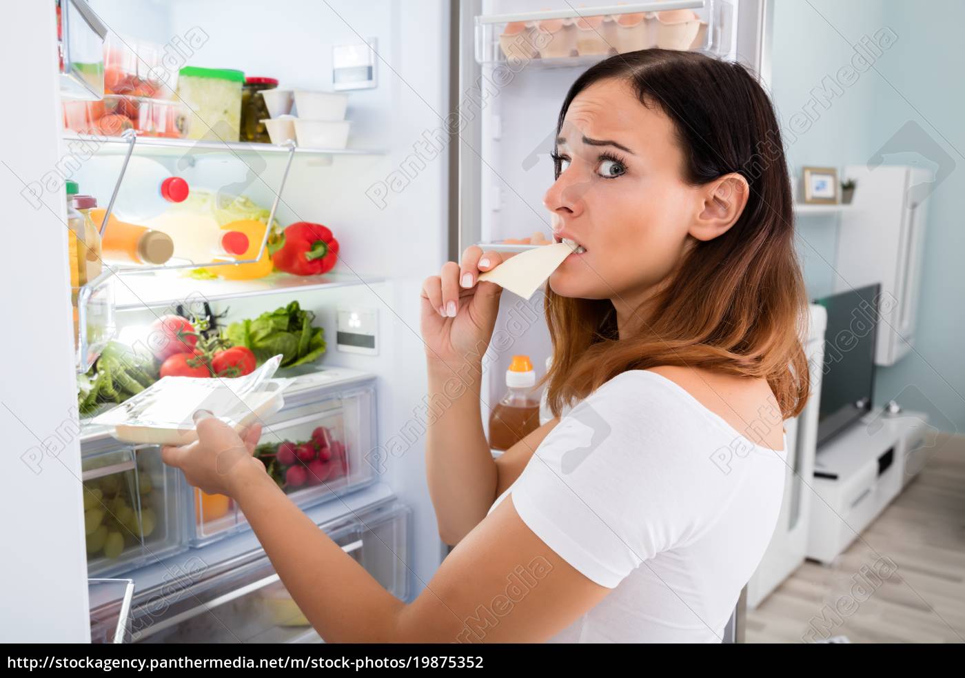 Mulher comendo queijo na frente da geladeira - Stockphoto #19875352 | Banco  de Imagens Panthermedia